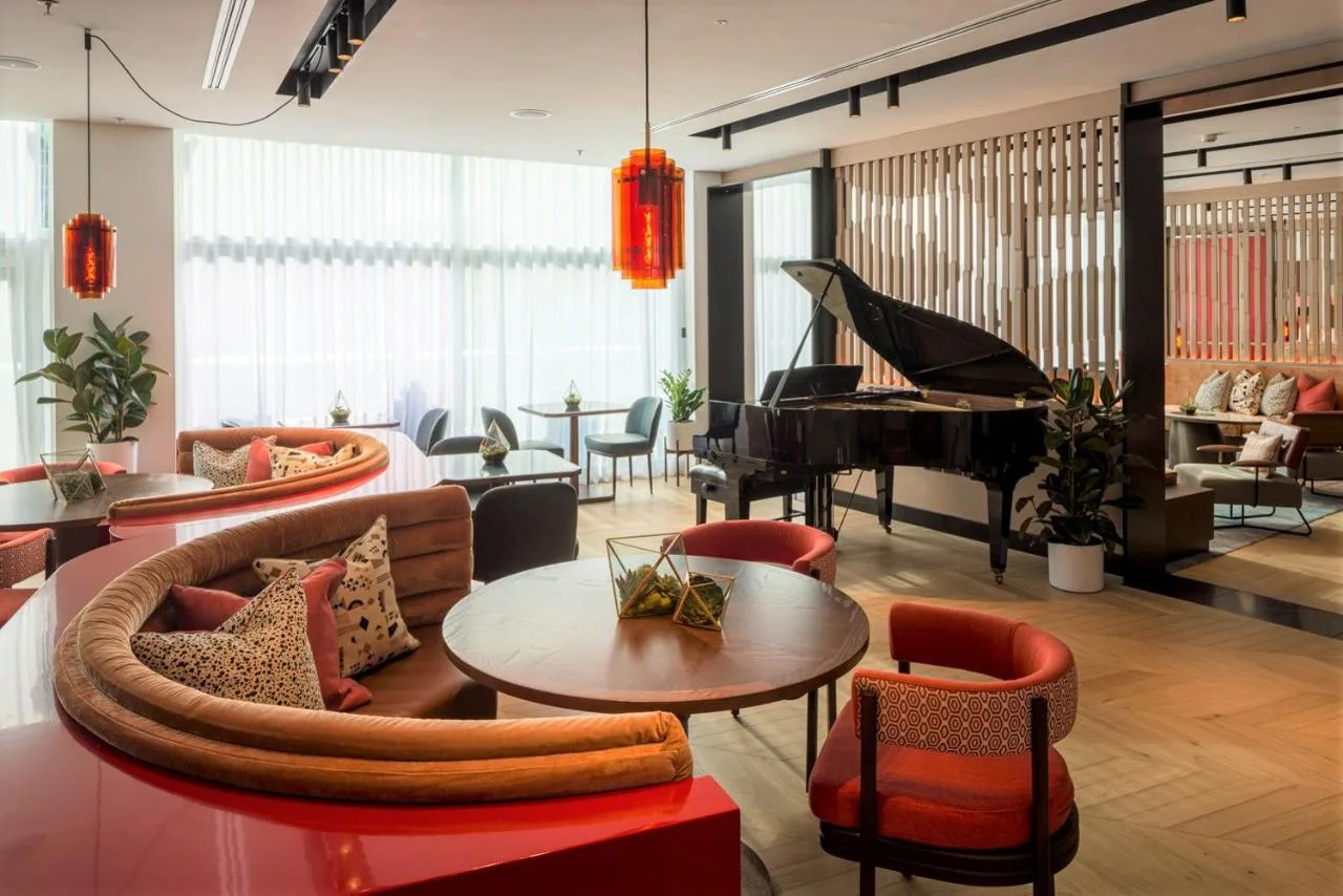 a living room filled with furniture and a piano at The Lowry Hotel Manchester in Manchester